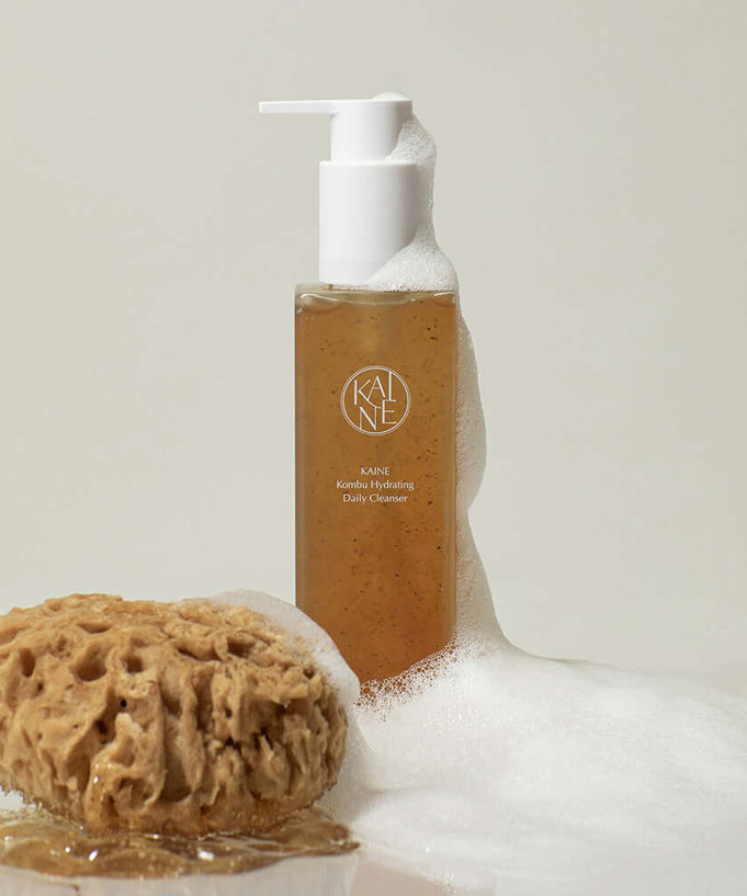 KAINE Kombu Hydrating Daily Cleanser 155g with foaming sponge beside the product bottle.