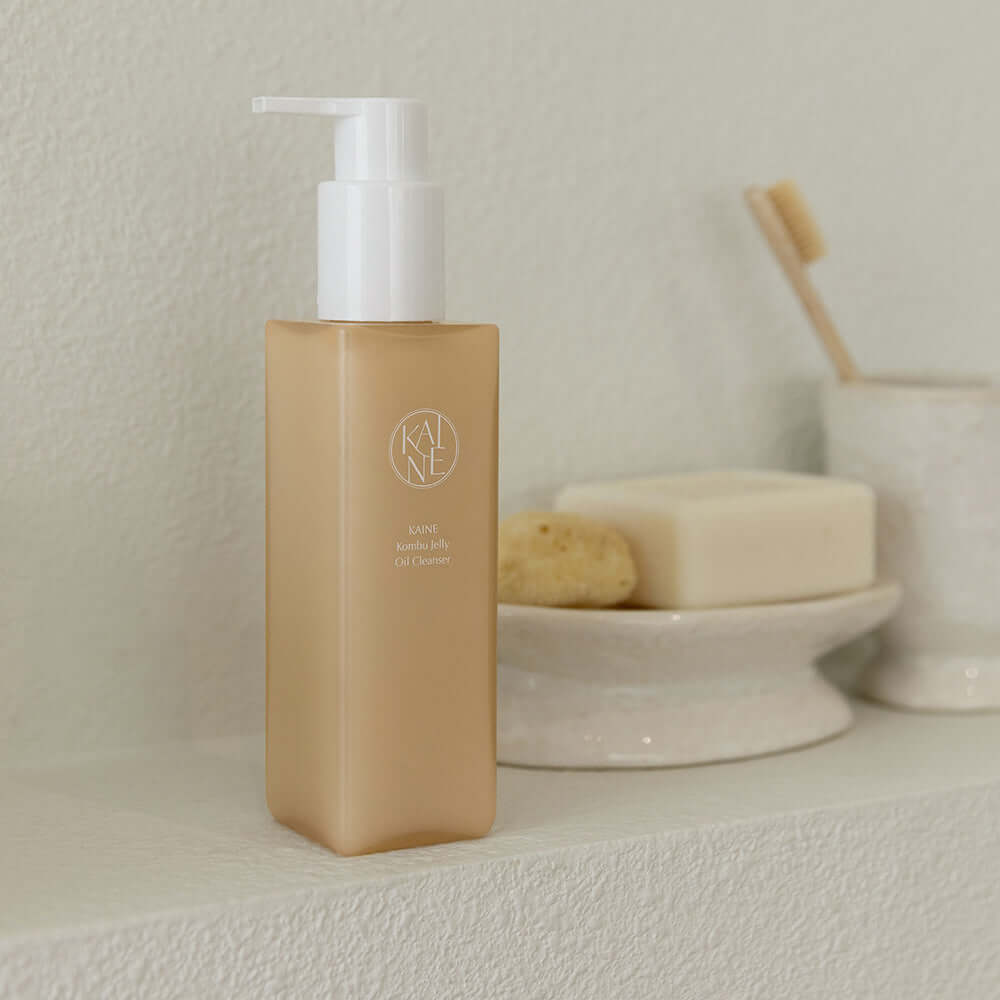 KAINE Kombu Jelly Oil Cleanser 145ml bottle on bathroom shelf surrounded by soap and sponge