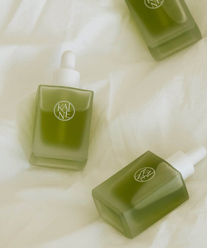 KAINE Rosemary AHA Night Serum 30ml bottles displayed on a soft fabric background, highlighting the product design and green packaging.