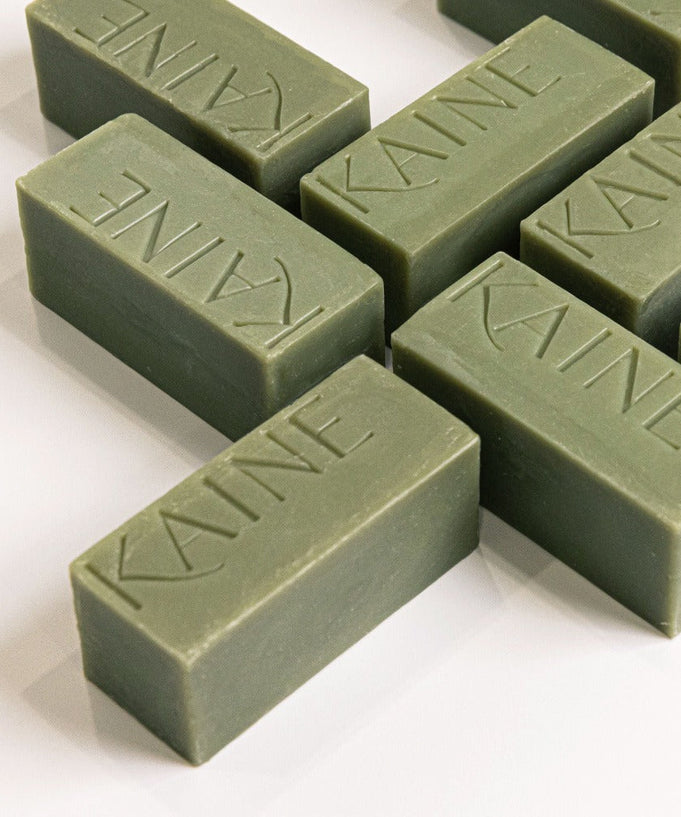 Image of multiple green bars of KAINE Rosemary Acne Mildly Acidic Cleansing Bar 100g, arranged on a white surface.