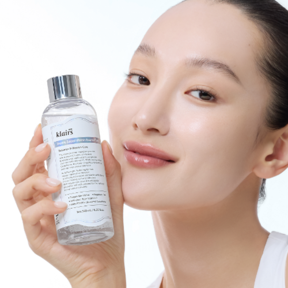 KLAIRS Freshly Juiced Vitamin Blemish Toner 180ml bottle held by smiling person.