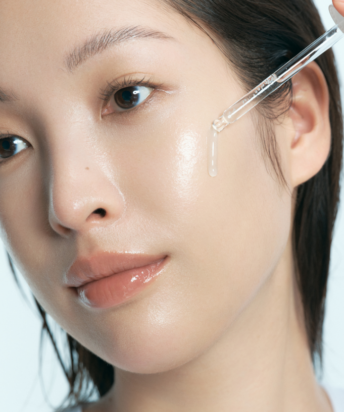 Model applying KLAIRS EGF Blue AC Soothing Serum 50g on face with dropper for glowing skin.