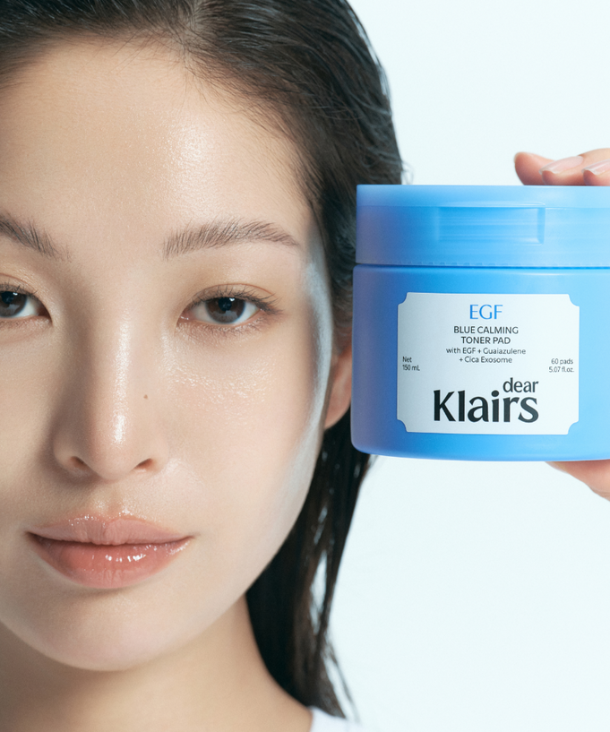 Woman holding KLAIRS EGF Blue Calming Toner Pads 60 Pads product jar, showcasing skincare benefits.