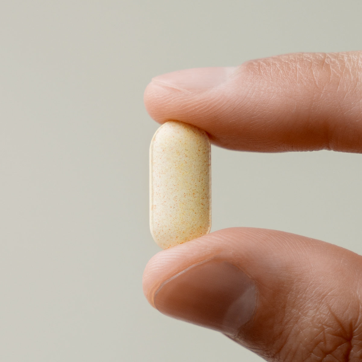 LAZY SOCIETY Multivitamin & Mineral Vitamin B 1000 single tablet held between fingers by Gentleman Korea for men’s supplement