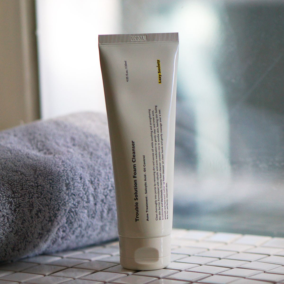 LAZY SOCIETY Trouble Solution Foam Cleanser 120ml tube on bathroom tile beside towel — Gentleman Korea men’s skincare product