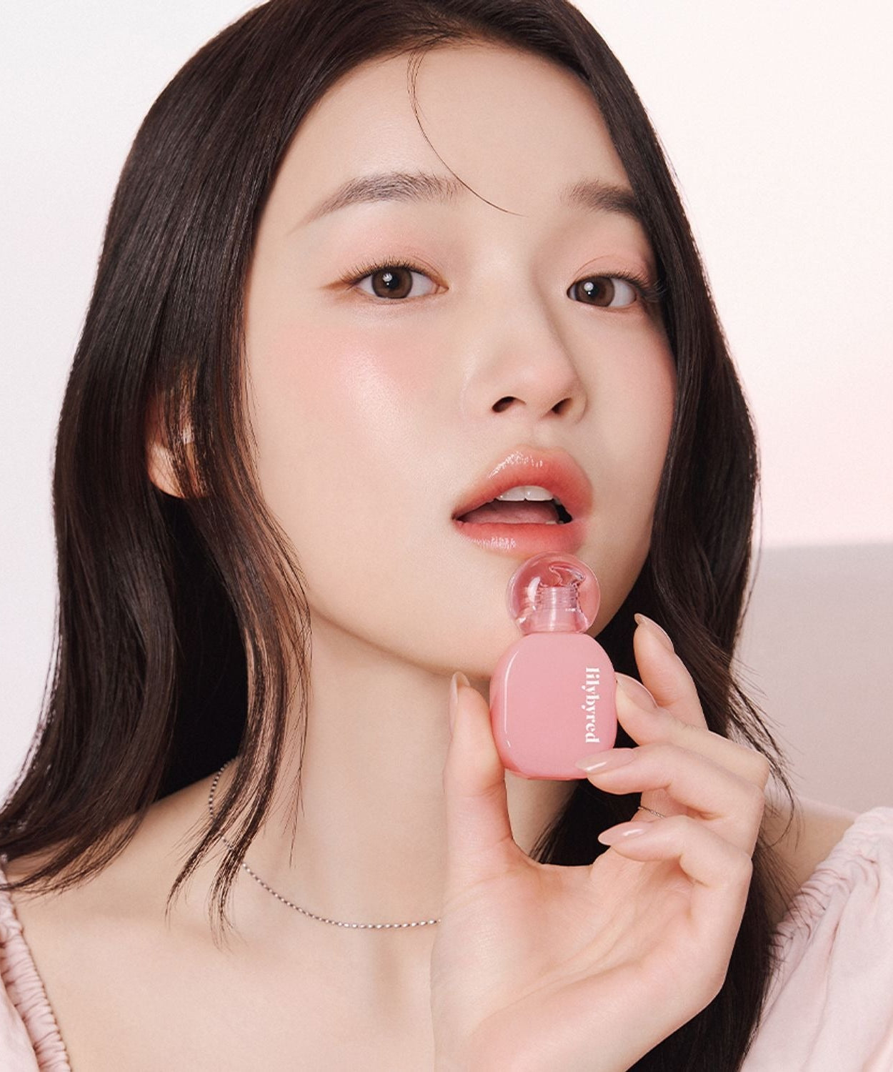 Woman applying LILYBYRED Balming Dewy Tint with a natural dewy finish.