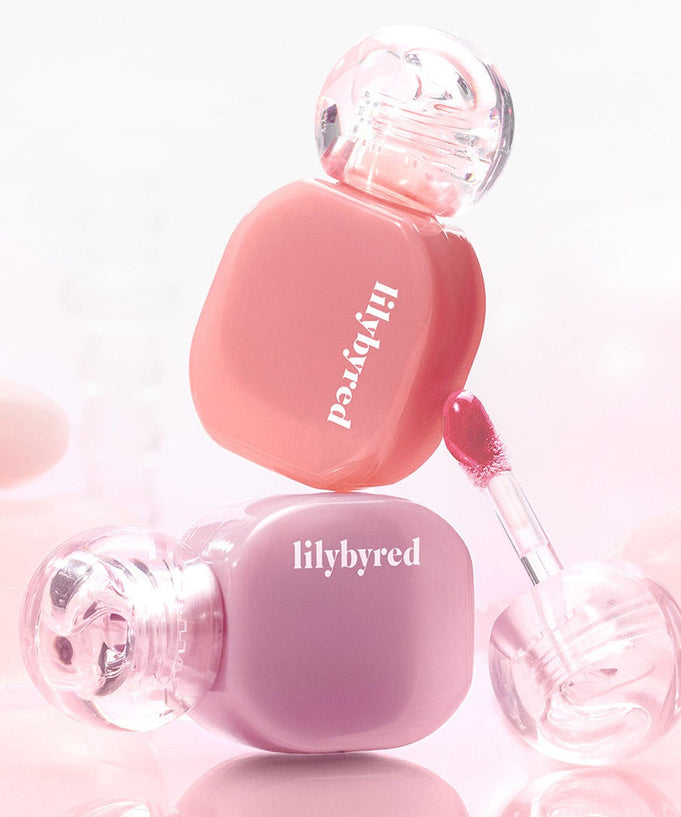 Two bottles of LILYBYRED Balming Dewy Tint in pink and purple shades with applicators, perfect for a glossy lip finish.