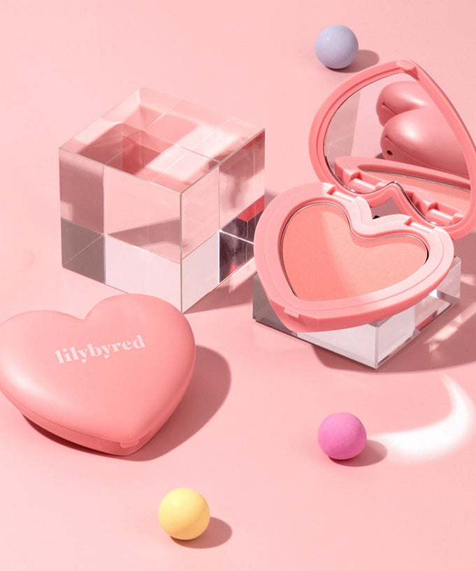 LILYBYRED Love Beam Cheek heart-shaped blush compact with mirror and decorative spheres on pink background