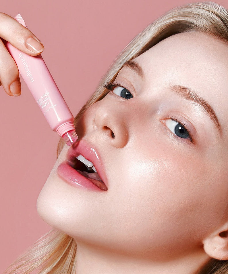 Woman applying MILK TOUCH Glow Up Collagen Lip Balm 15g on lips for a radiant look.