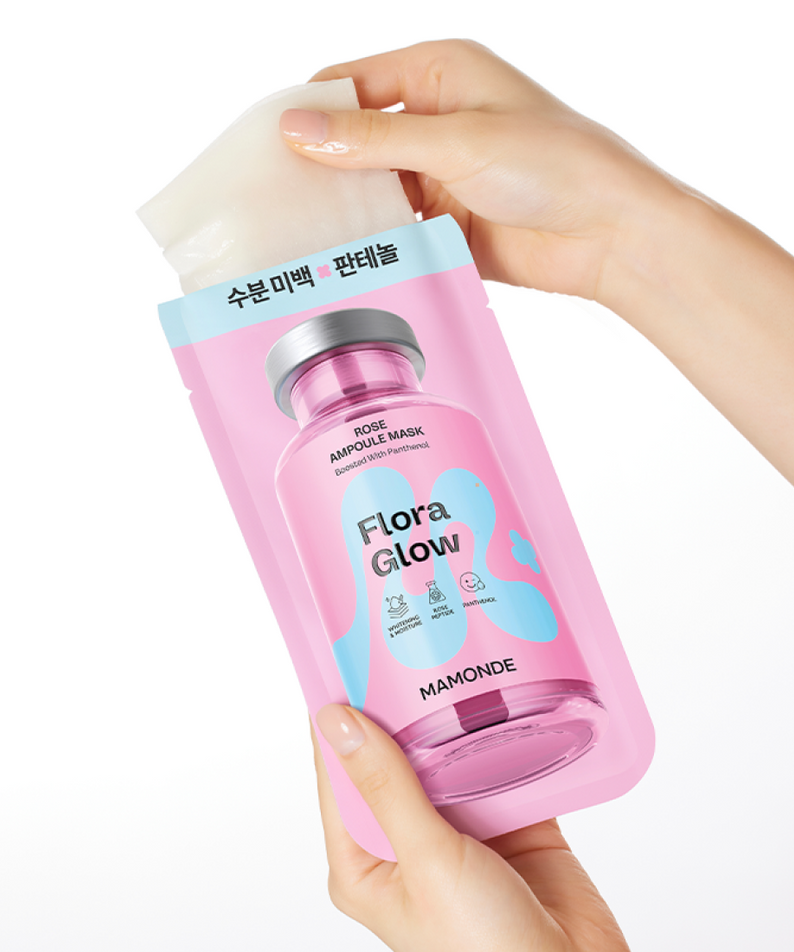 Hands holding MAMONDE Flora Glow Rose Ampoule Mask Pack, featuring a pink bottle design with blue accents.
