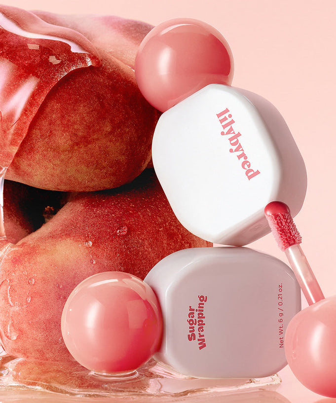 LILIBYRED Sugar Wrapping Tint Gloss with peach backdrop showcasing lip gloss texture and luxury packaging.