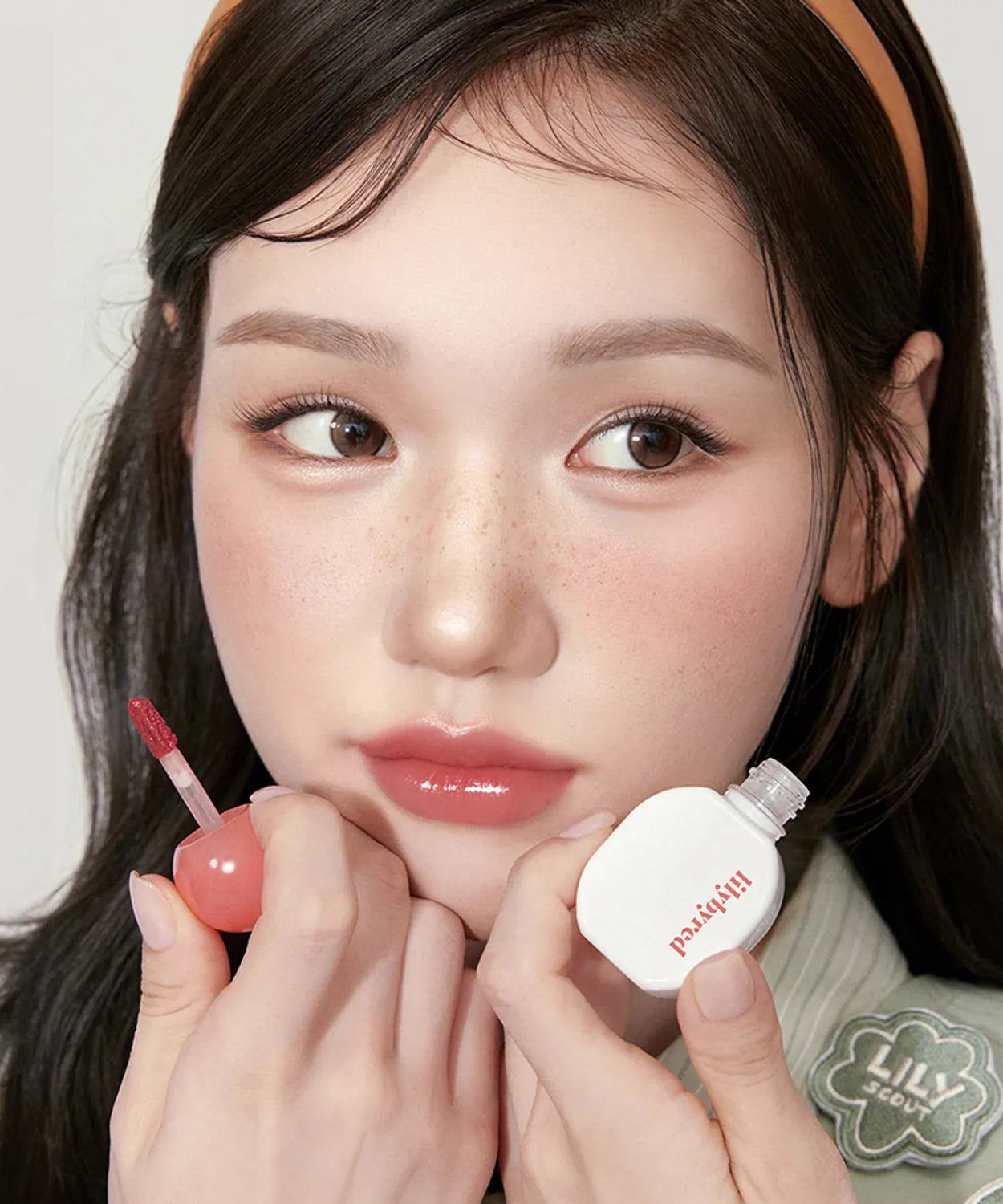 Model applying LILIBYRED Sugar Wrapping Tint Gloss showing glossy and vibrant lip color.