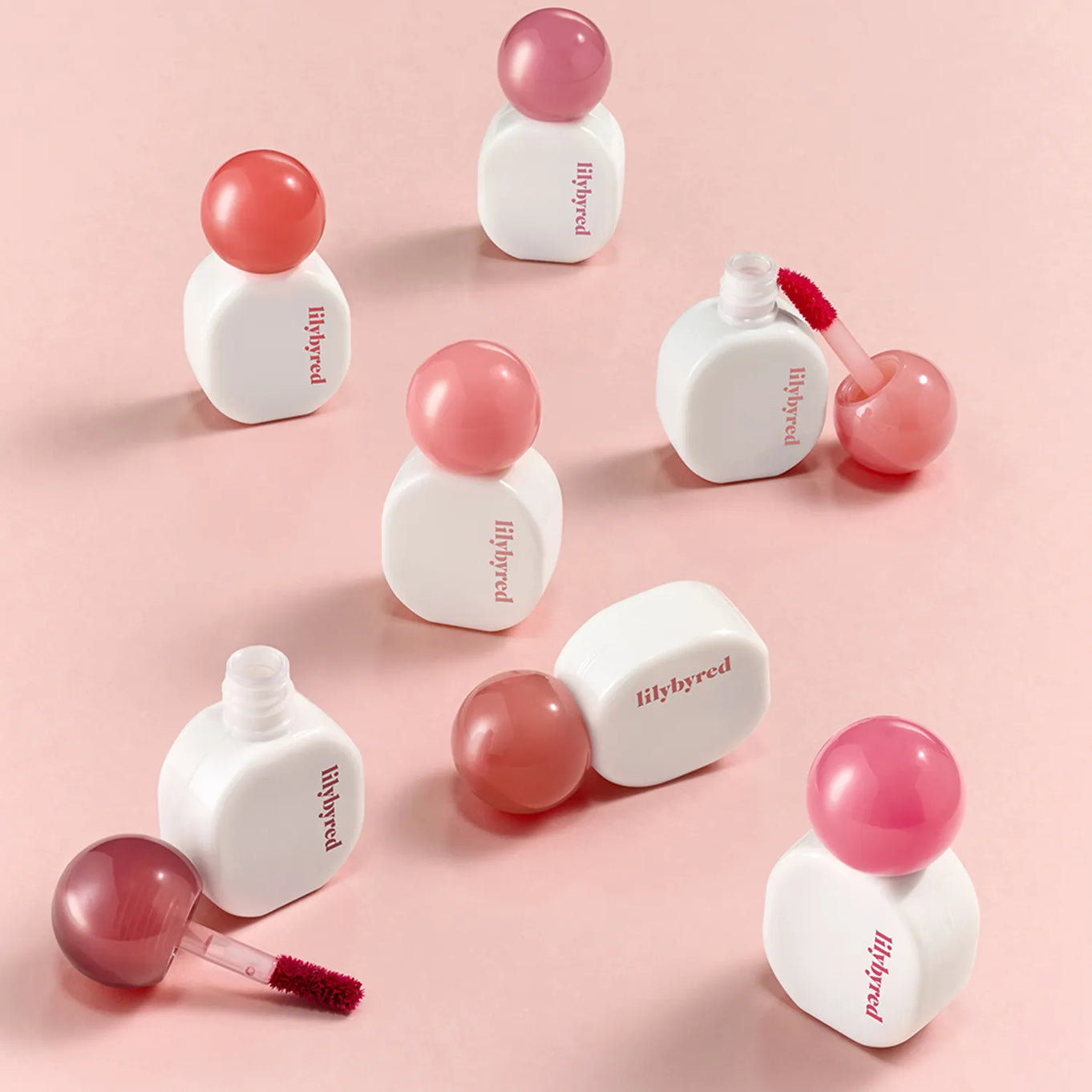 LILIBYRED Sugar Wrapping Tint Gloss bottles displayed on a pink background, highlighting the vibrant color options and sleek design.