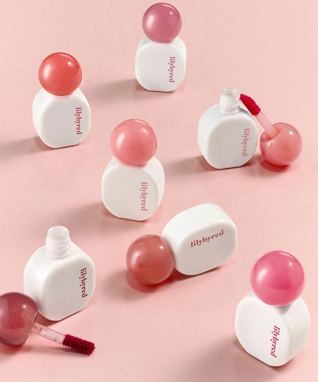 LILIBYRED Sugar Wrapping Tint Gloss bottles displayed on a pink background, highlighting the vibrant color options and sleek design.