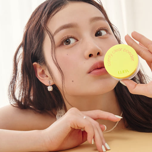 Woman holding LUNA Comfy Clear Powder in hand, showcasing beauty product.