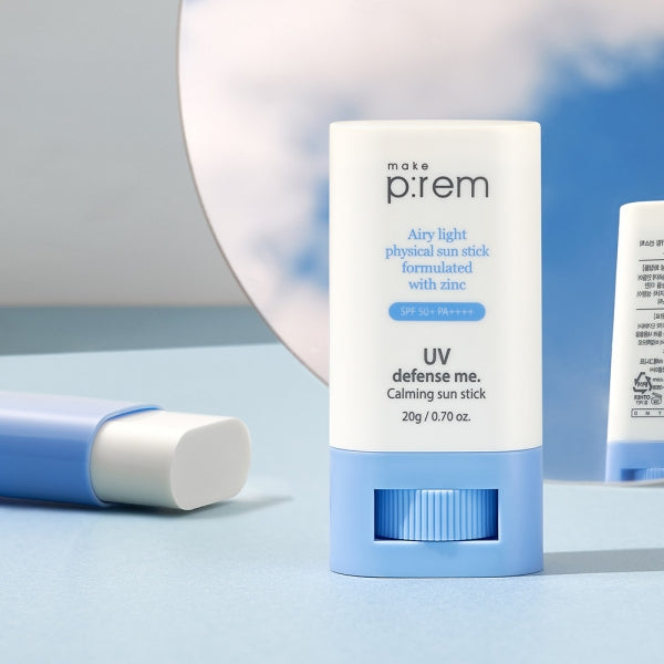 MAKE P:REM UV Defense Me Calming Sun Stick 20g on a blue surface with a reflective mirror background.