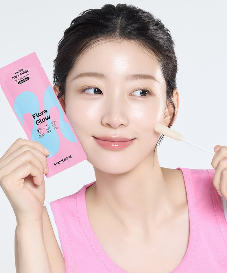 Smiling woman applying MAMONDE Flora Glow Rose Ball Mask 3.5ml on face, holding mask sachet.