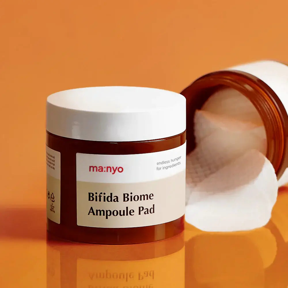 MANYO Bifida Biome Ampoule Pad 70 Sheets on an orange background with opened lid and visible cotton pads.
