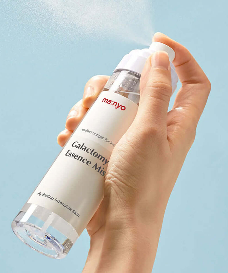 MANYO Galactomy Essence Mist 120ml being sprayed, showcasing hydrating benefits for intensive skin care on a light blue background.