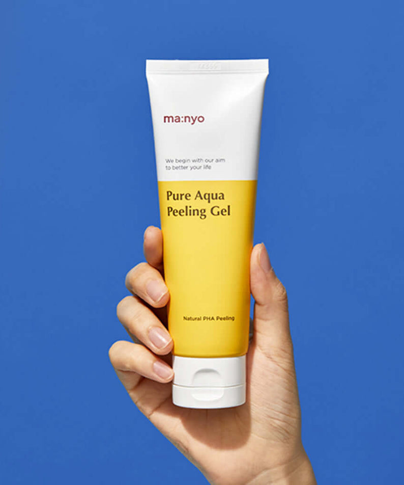 Hand holding MANYO Pure Aqua Peeling Gel 120ml against blue background