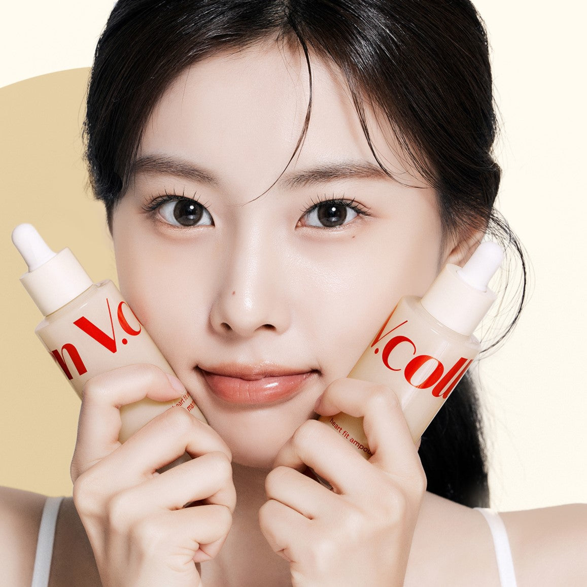 Woman holding two bottles of MA:NYO V.Collagen Heart Fit Ampoule 50ml in front of her face.