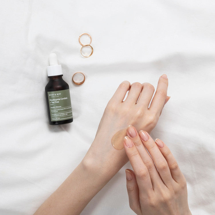Applying MARY & MAY Houttuynia Cordata + Tea Tree Serum 30ml to skin with jewelry on bed