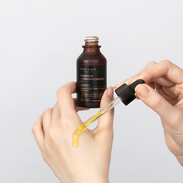 Hands applying MARY & MAY Idebenone + Blackberry Complex Serum 30ml with dropper