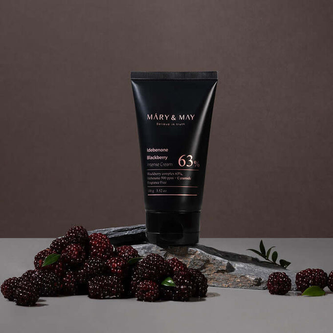 MARY & MAY Idebenone Blackberry Intense Cream surrounded by fresh blackberries on a stone surface.