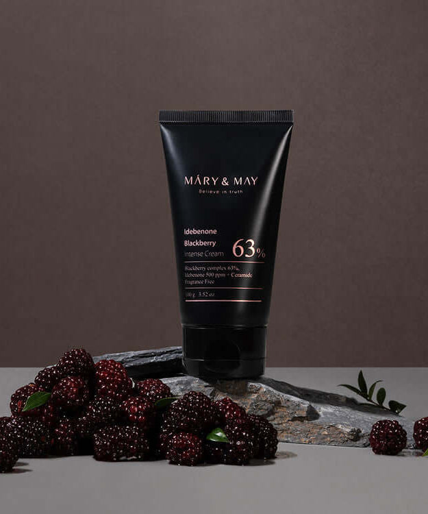 MARY & MAY Idebenone Blackberry Intense Cream surrounded by fresh blackberries on a stone surface.