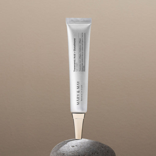 MARY & MAY Tranexamic Acid + Glutathione Eye Cream 30g tube on stone, anti-aging skincare product for dark circles and puffiness.