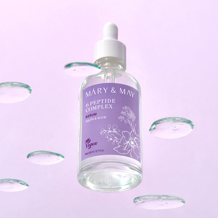 Bottle of MARY&MAY 6 Peptide Complex Serum 80ml against a soft purple background with water droplets.