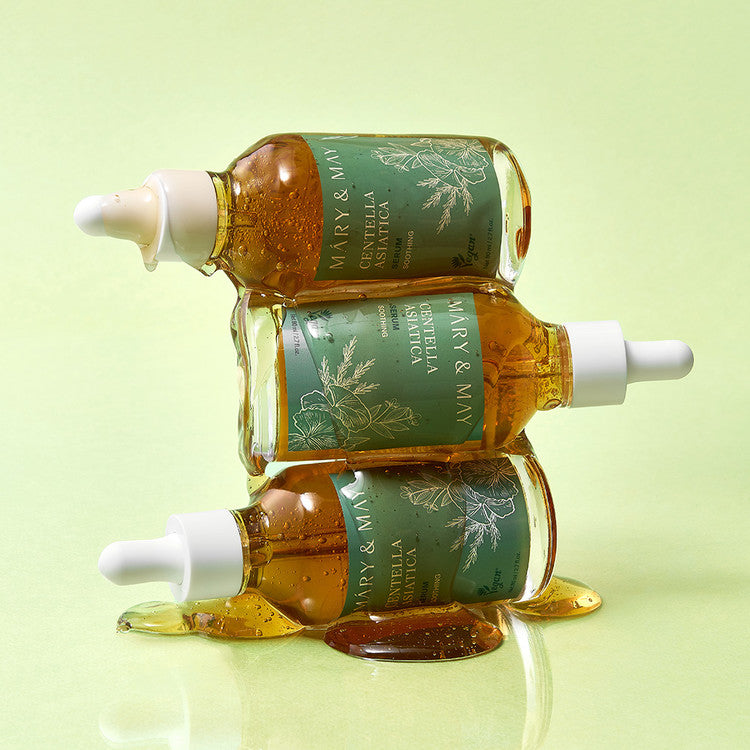 Three bottles of MARY&MAY Herbal Extract Serum 80ml with droppers on a green background, showcasing product design and packaging.