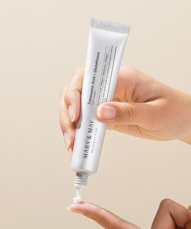 Hand holding tube of MARY&MAY Tranexamic Acid Glutathione Eye Cream 30ml