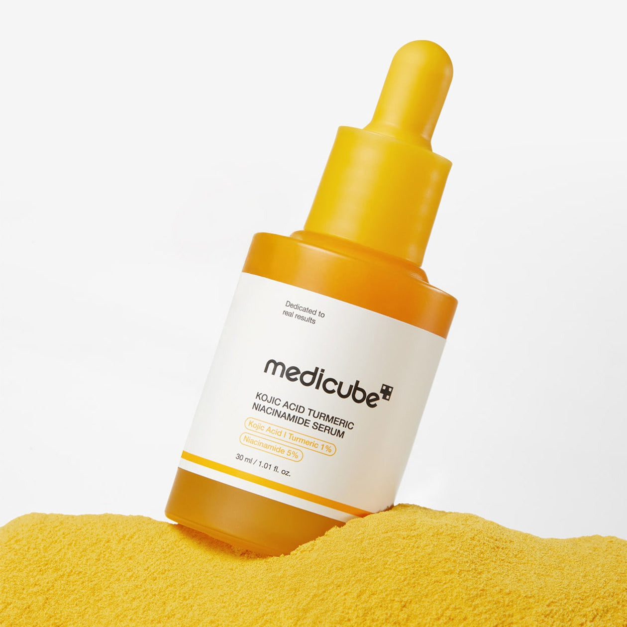 MEDICUBE Kojic Acid Turmeric Vita Serum 30ml bottle on yellow powder background