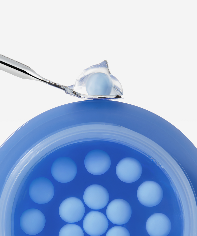 Close-up of MEDICUBE Hyaluronic Moisturizing Capsule Cream 55g showing the cream and capsules in a blue container with a scoop.