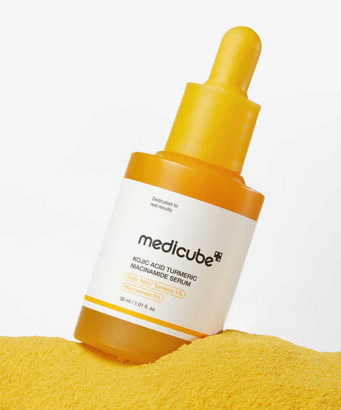 MEDICUBE Kojic Acid Turmeric Vita Serum 30ml bottle on yellow powder background