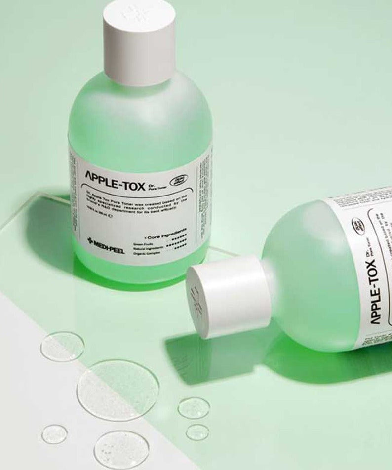 Two bottles of MEDIPEEL Dr.Apple Tox Pore Toner 500ml on a green background with liquid droplets.