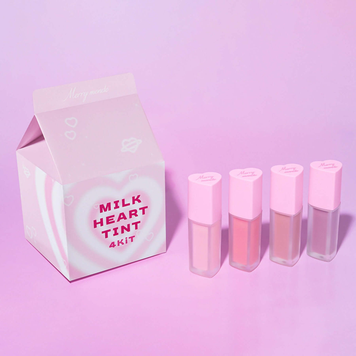 MERRYMONDE Milk Heart Tint 4 Kit Â in pastel pink packaging with four lip tint bottles on a pink background.