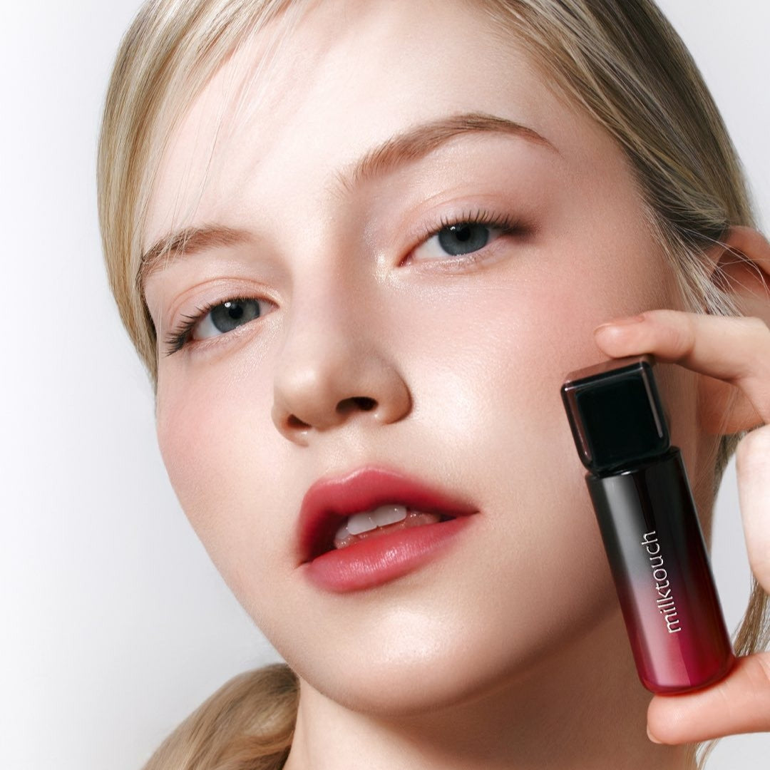 Model holding MILK TOUCH Black Peel-Off Lip Tattoo showing red lip color effect.
