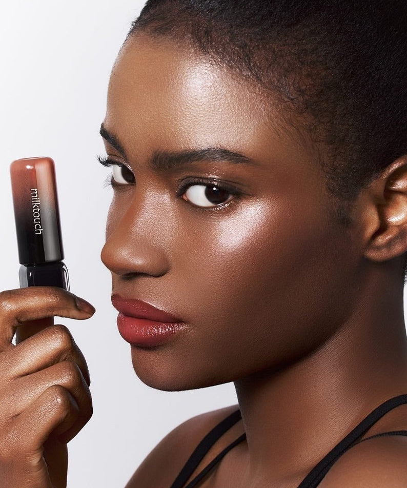 Model showcasing MILK TOUCH Black Peel-Off Lip Tattoo in hand, highlighting its vibrant color and peel-off application.