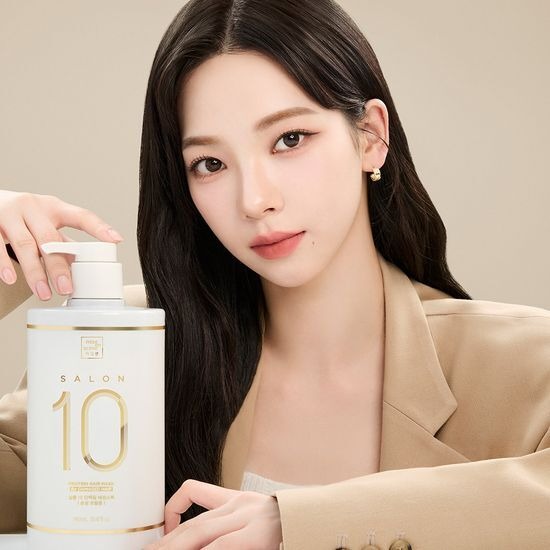 Person holding MISE EN SCENE Salon 10 Protein Treatment Essence Pack 990ML in a beige setting.