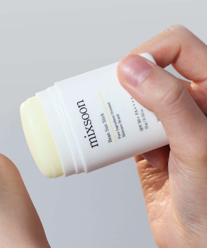 Hand applying MIXSOON Bean Sun Stick for sun protection and skincare