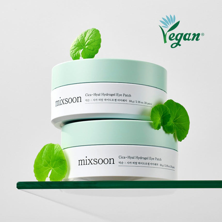 MIXSOON Cica Hyal Hydrogel Eye Patch 60 Sheets on display with green leaves on a glass surface, featuring vegan certification.