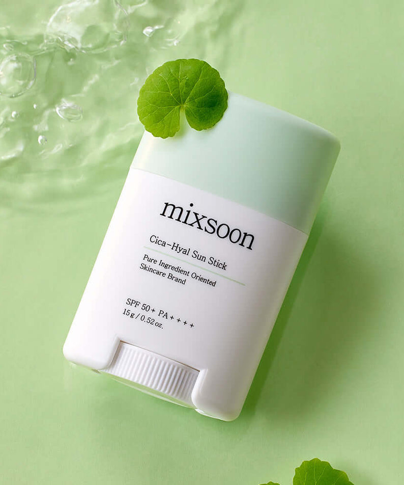 MIXSOON Cica Hyal Sun Stick with green cap, SPF 50+, on a light green background, surrounded by water droplets and a leaf.