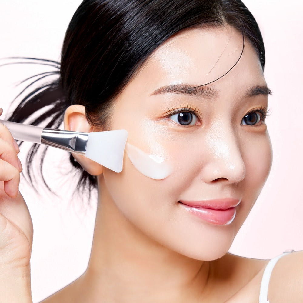 Woman applying MIXSOON Collagen Glass Skin Mask 80ml to her face with a brush for radiant complexion.