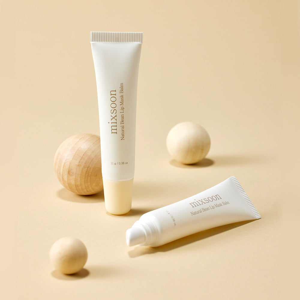 MIXSOON Natural Bean Lip Mask bean, featuring two tubes amidst decorative wooden spheres on a beige background