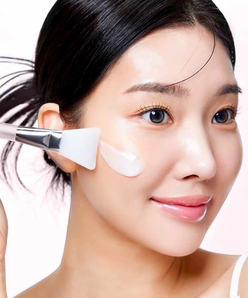 Woman applying MIXSOON Collagen Glass Skin Mask 80ml to her face with a brush for radiant complexion.