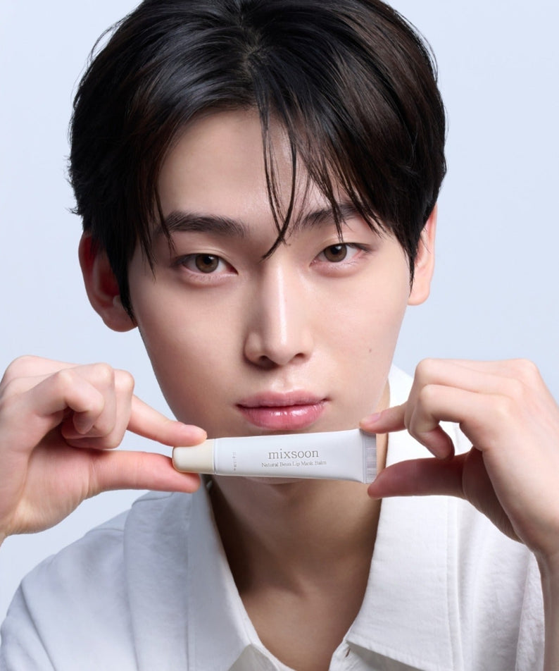 Person holding MIXSOON Natural Bean Lip Mask bean in a tube up to their face, showcasing skincare product.