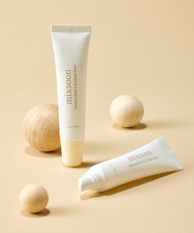 MIXSOON Natural Bean Lip Mask bean, featuring two tubes amidst decorative wooden spheres on a beige background