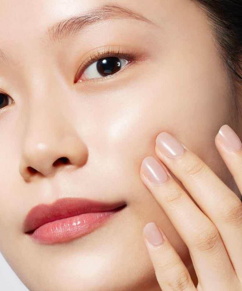 Model applying MOONSHOT Magnetic Black Cleansing Oil on skin for radiant complexion.